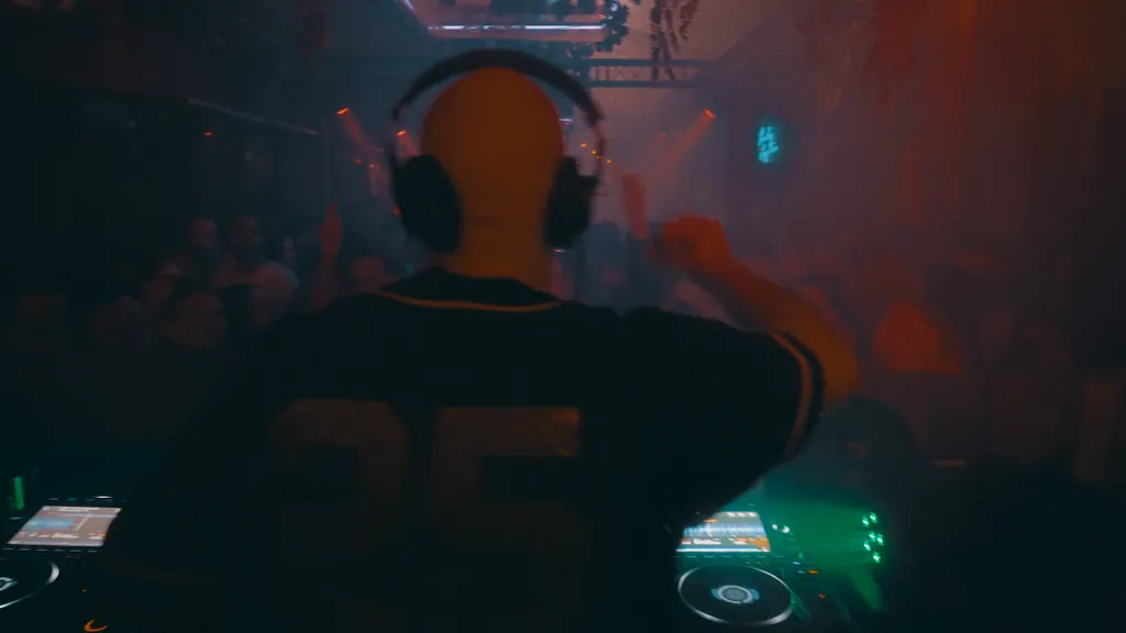 DJ achter de booth met zicht op het publiek bij De Gin
