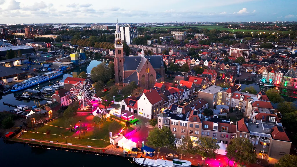 Dronebeeld van Maassluis bij avond met de Grote Kerk, de haven en de kermis